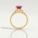 Viola shoulder-set engagement ring in 18k yellow gold with an oval pink lab-grown sapphire centre stone and diamond accents, side profile showing the setting and band.
