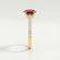 Viola shoulder-set engagement ring in 18k yellow gold with an oval lab-grown ruby centre stone and diamond accents, end-on view showing the setting and band.