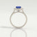 Violette halo engagement ring with a cushion blue lab-grown sapphire centre stone and diamond accents, side profile showing the setting and band.