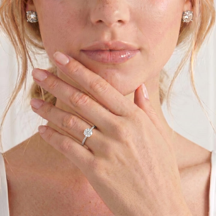 Video showing the Macy petite shoulder-set engagement ring with a round moissanite centre stone and diamond accents worn on a model's hand.