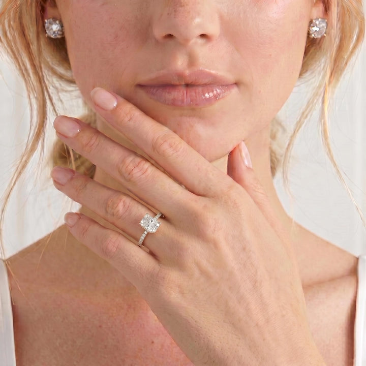 Video showing the Lively petite hidden halo engagement ring with a radiant moissanite centre stone and diamond accents on a pavé-set band worn on a model's hand.