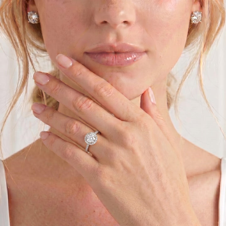 Video showing the Lavender petite halo engagement ring with a round moissanite centre stone and diamond accents worn on a model's hand.